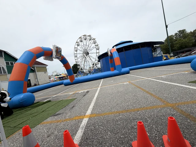 The track set up on fairground blacktop with a Ferris wheel and fair buildings behind it